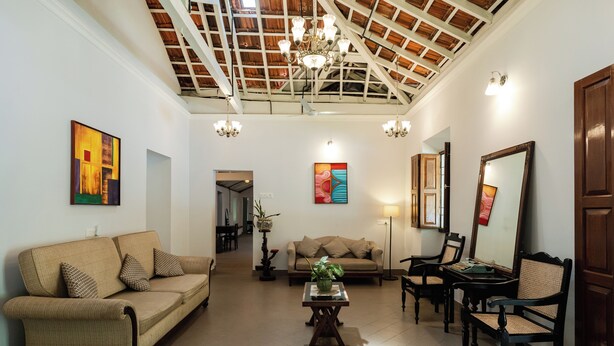 A spacious living room with a high ceiling, a sofa, a coffee table, and a dining area. - Casa Particular in Cansaulim, India (Arossim)