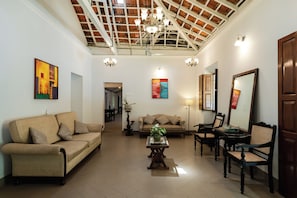 A spacious living room with a high ceiling, a sofa, a coffee table, and a dining area.