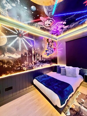 Ein Schlafzimmer mit einem großen Bett, einem Wandgemälde eines Schlosses und einer Mickey Mouse Figur.