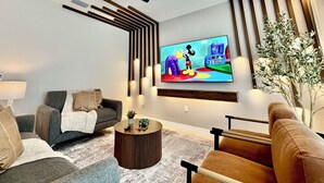 A modern living room with a sofa, armchair, coffee table, and a flat-screen TV mounted on the wall. - 401 - Beyond the Sea & Into the Stars (Kissimmee)