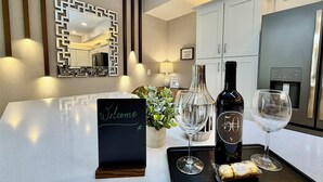 A modern kitchen with a countertop, a welcome sign, a wine bottle, two wine glasses, and a tray with a cork. - 401 - Beyond the Sea & Into the Stars (Kissimmee)