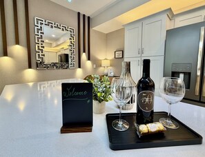 A modern kitchen with a countertop, a welcome sign, a wine bottle, two wine glasses, and a tray with a cork. - 401 - Beyond the Sea & Into the Stars (Kissimmee)