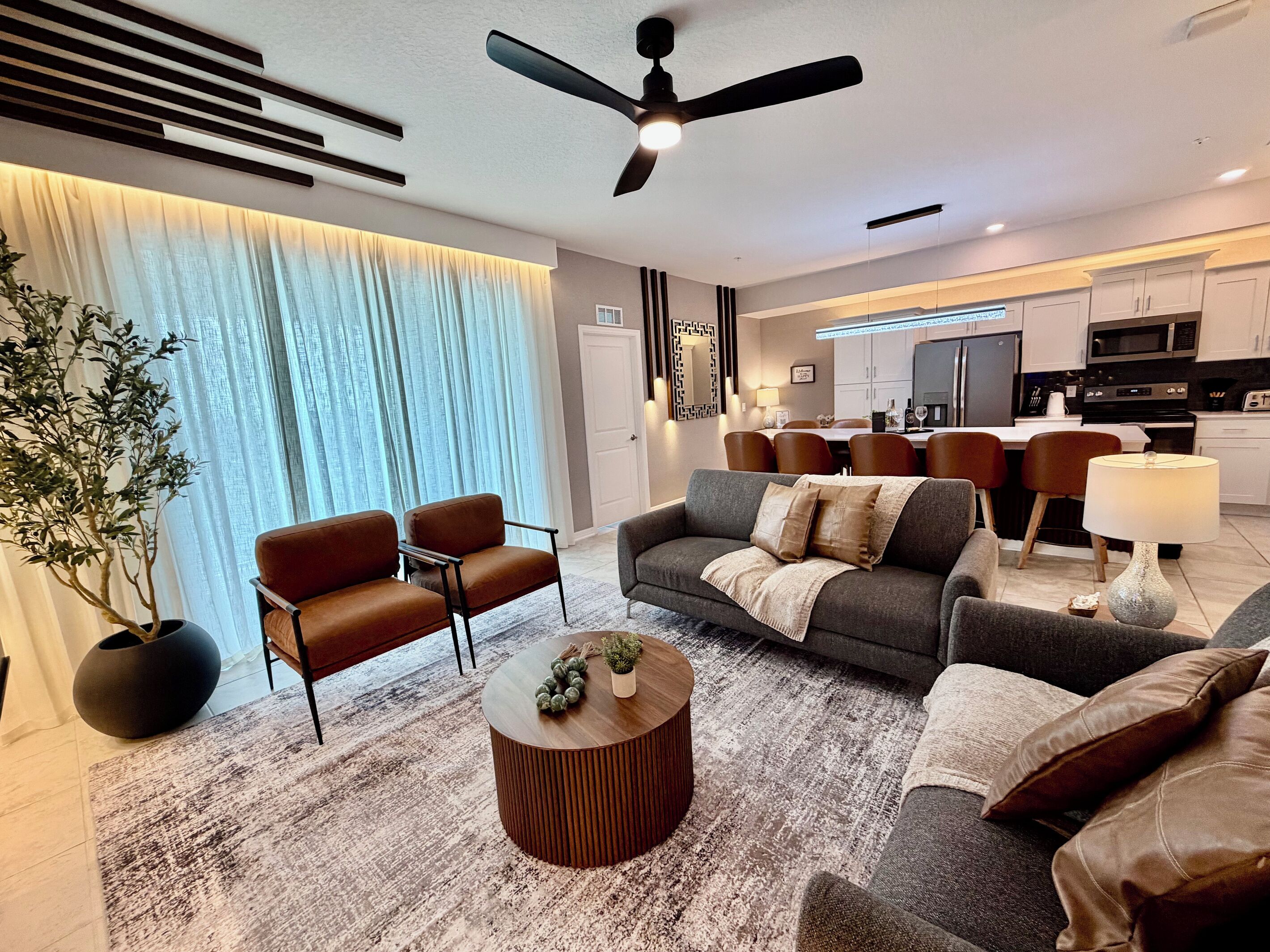 Ein modernes Wohnzimmer mit einer Couch, Sesseln, einem Couchtisch und einem Essbereich mit Stühlen und Tisch.