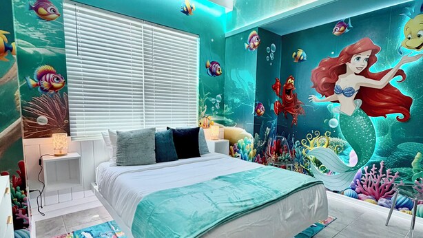 A bedroom with a bed, a ceiling fan, and a mural of a mermaid. - 401 - Beyond the Sea & Into the Stars (Kissimmee)