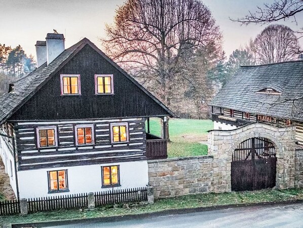 Une maison à deux étages avec un mur en pierre et un portail en bois.