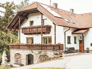 Un chalet traditionnel avec une façade en pierre, un balcon en bois et une cheminée en pierre.