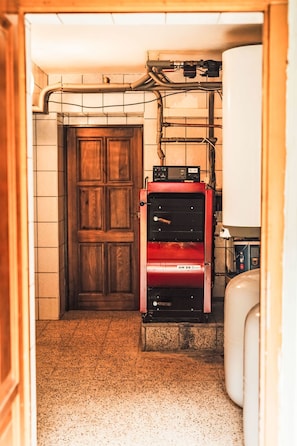 Une pièce avec une porte en bois, un appareil électroménager rouge et un réservoir d’eau blanc.