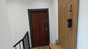Ein Korridor mit einer hölzernen Bank, einem Kleiderständer mit einem Regenschirm und einer Tür, die mit der Nummer 1 gekennzeichnet ist.