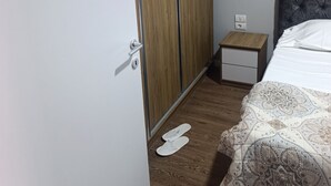 Ein Schlafzimmer mit einem Bett, einem Kleiderschrank, einem Nachttisch und Hausschuhen auf dem Boden.