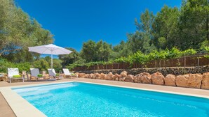 A swimming pool with clear blue water, surrounded by a stone wall and greenery. - Es Tancat Prim - Villa With Private Pool (Algaida)