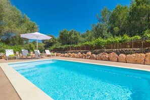 A swimming pool with clear blue water, surrounded by a stone wall and greenery. - Es Tancat Prim - Villa With Private Pool (Algaida)