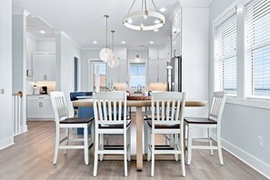A modern kitchen with white cabinetry, a central island, and pendant lighting. - Shore Perfection | Family Beach Retreat, Sleeps 8 (Emerald Isle)