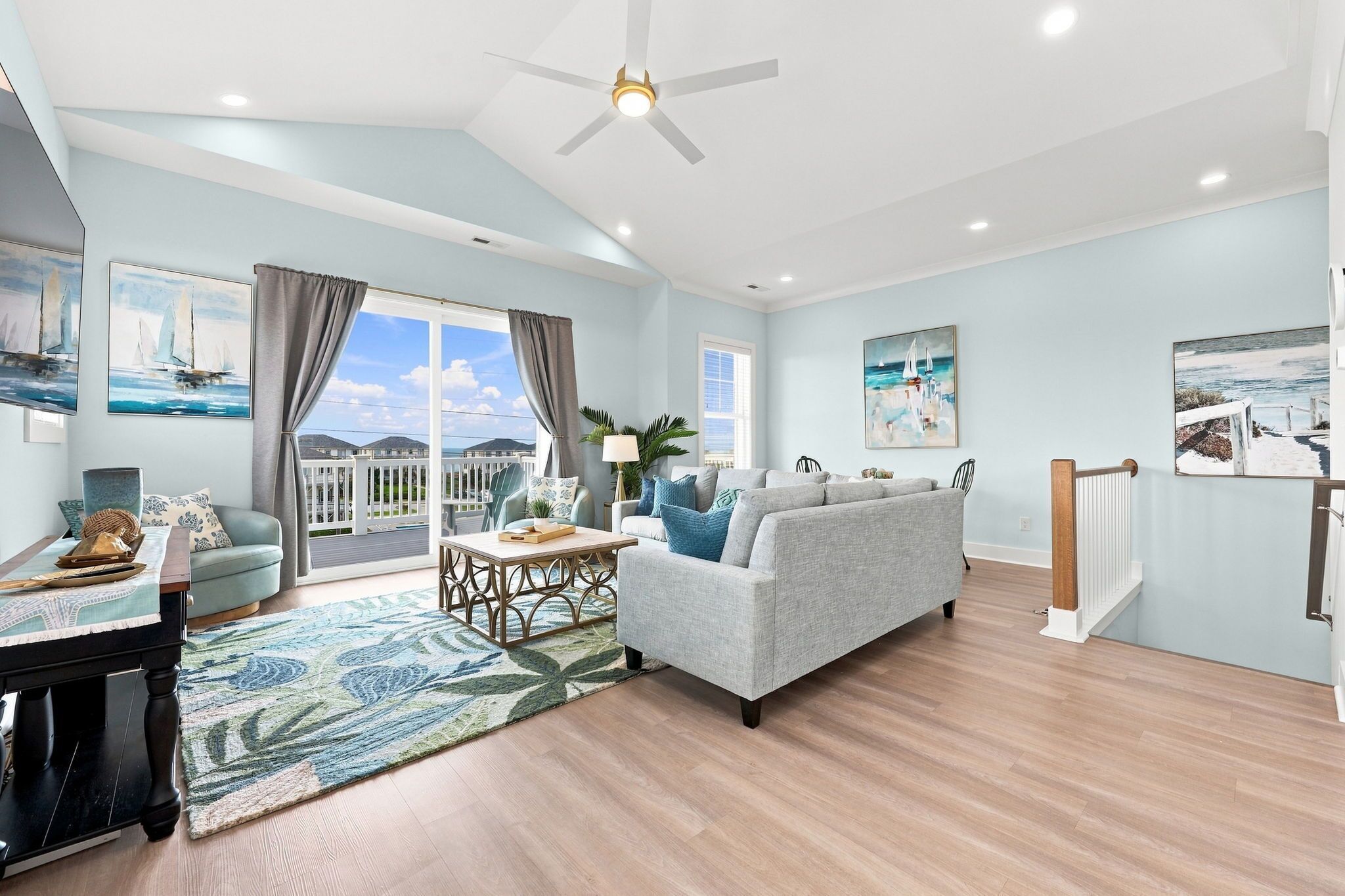 A spacious living room with a large window, a ceiling fan, and a view of the outdoors.