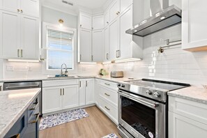 A modern kitchen with white cabinetry, a stainless steel range, and a built-in oven. - Shore Perfection | Family Beach Retreat, Sleeps 8 (Emerald Isle)