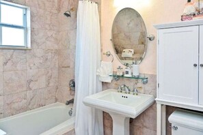 Ein Badezimmer mit einer Badewanne, einem Waschbecken, einem Spiegel und einem Schrank.