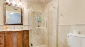 Ein Badezimmer mit Duschkabine, Toilette und Waschtisch mit Spiegel und Beleuchtung.