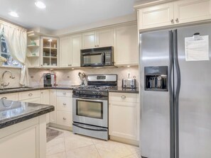 A kitchen with a stainless steel refrigerator, a microwave, a stove, and a sink. - The Lions House from 1924 (West Palm Beach)