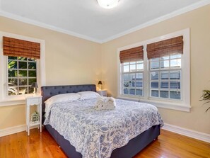 A bedroom with a large bed, two bedside tables, and windows with blinds. - The Lions House from 1924 (West Palm Beach)