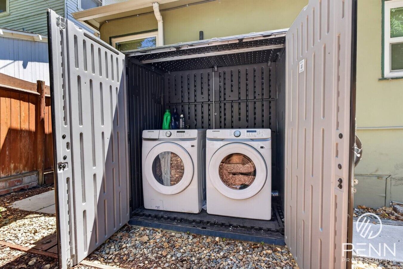 A portable laundry unit with two washing machines, a metal rack, and a small green bottle.