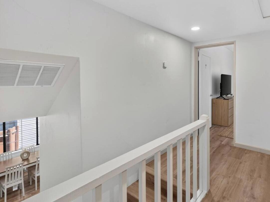 A room with a white ceiling, a white railing, and a wooden floor.