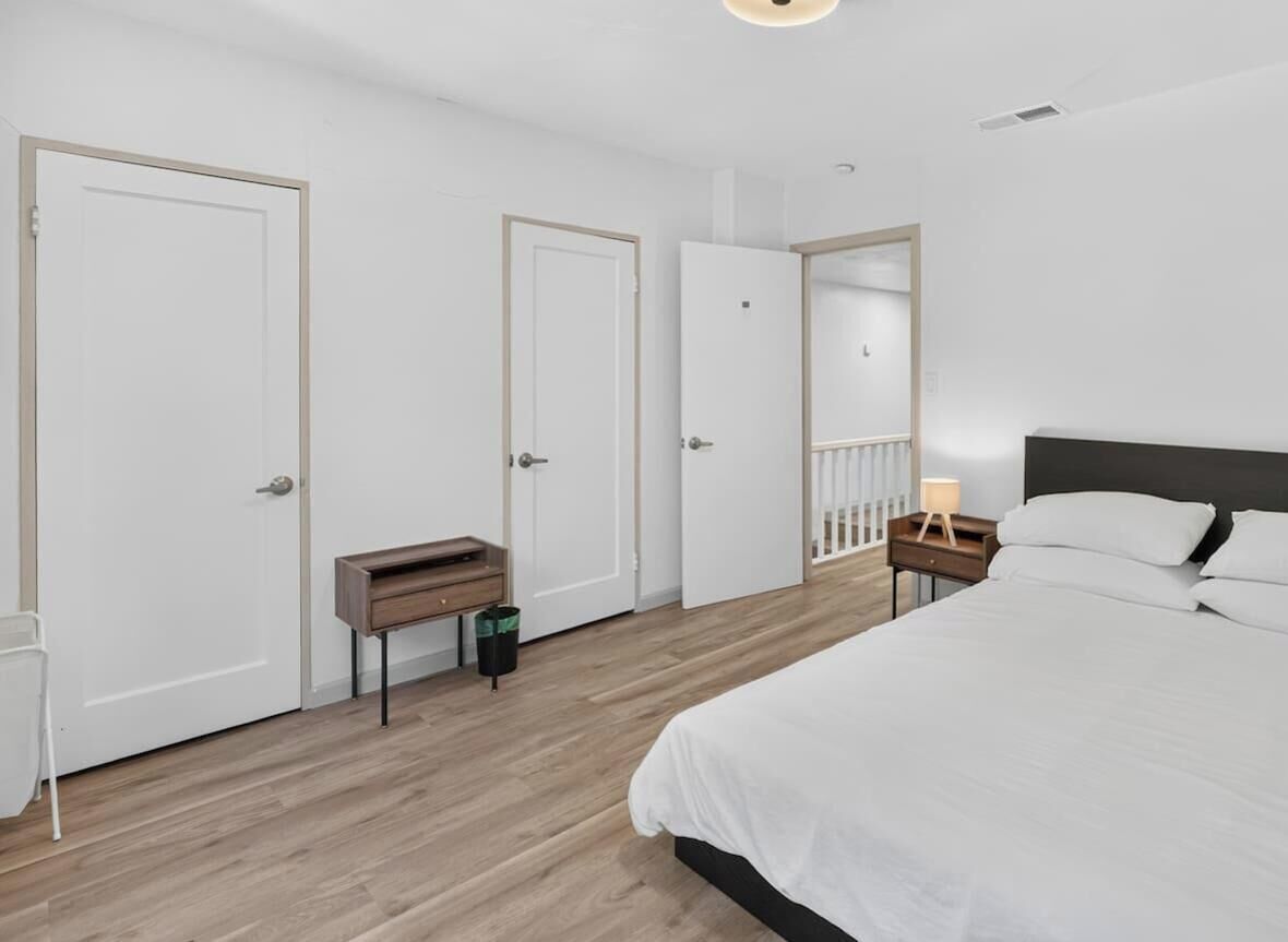 A bedroom with a bed, a nightstand, a mirror, and a door.