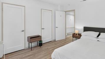A bedroom with a bed, a nightstand, a mirror, and a door.