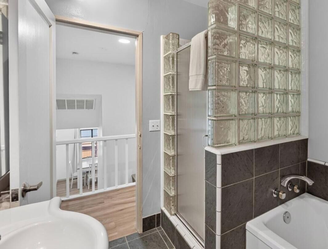 A bathroom with a glass shower enclosure, a bathtub, and a white sink.
