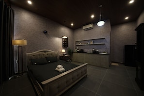 Ein Schlafzimmer mit Bett, Nachttisch, Lampe und einer kleinen Küchenzeile.