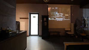 A modern interior with a kitchen area, a projection screen displaying text, and a seating area with a bench and chairs. - Ala Homestay Can Tho - Vincom Xuan Khanh (Can Tho)