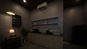 A dimly lit kitchen with a built-in stove, a small dining table with a lamp, and a potted plant. - Ala Homestay Can Tho - Vincom Xuan Khanh (Can Tho)