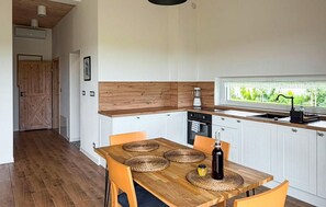 Eine moderne Küche mit einem Holztisch, Stühlen und Blick auf Grünfläche.