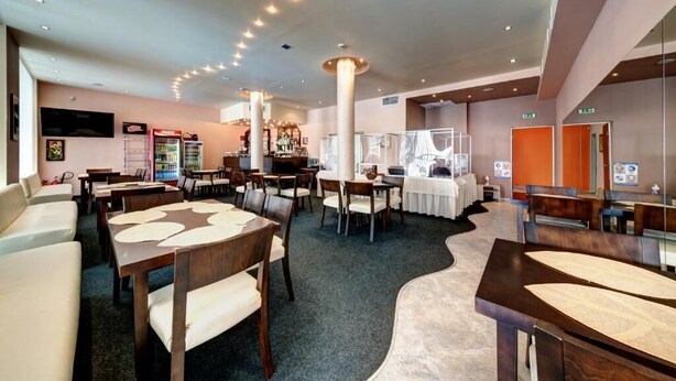 A hotel lobby with multiple seating areas, a bar, and a reception desk. - Hotel Sveti Nikolai (Primorsko)
