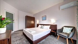 A hotel room with a bed, bedside table, chair, and a potted plant. - Hotel Sveti Nikolai (Primorsko)