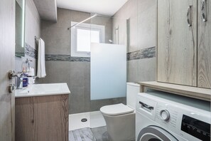 A modern bathroom with a sink, mirror, toilet, and washing machine. - Modern 2BR Apt in Oroklini Larnaca (Voroklini)