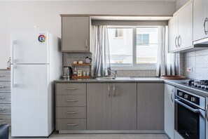 A compact kitchen with a refrigerator, stove, and sink. - Modern 2BR Apt in Oroklini Larnaca (Voroklini)
