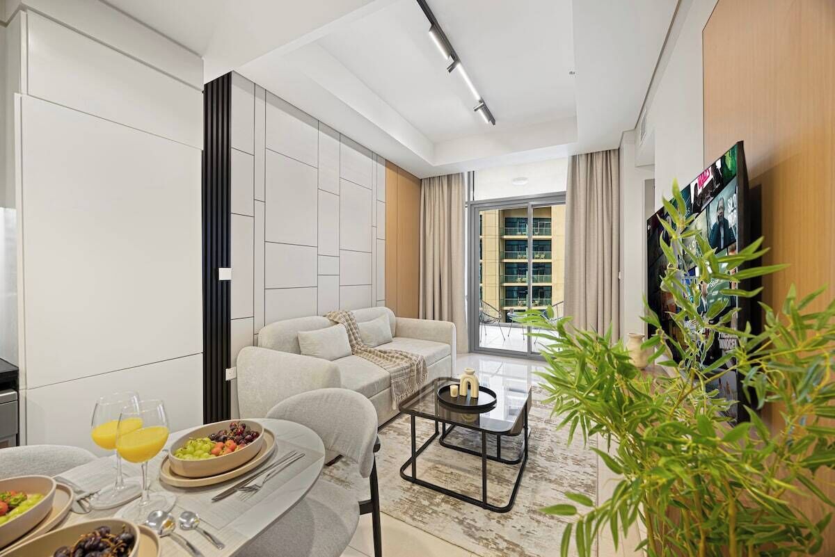 A modern living room with a sofa, coffee table, and dining area with a breakfast setup.