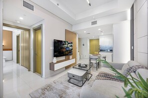 A modern living room with a flat-screen TV, a sofa, a coffee table, and a dining area with a small table and chairs. - Skyline View Apt in Business Bay w/Pool & Sauna (Dubai)