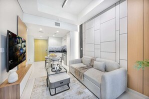 A modern living room with a sofa, a coffee table, and a TV mounted on the wall. - Skyline View Apt in Business Bay w/Pool & Sauna (Dubai)