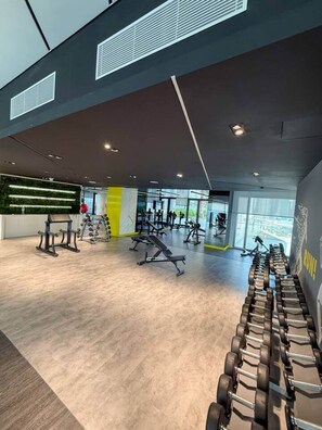 A gym with various exercise equipment, including dumbbells and benches. - Skyline View Apt in Business Bay w/Pool & Sauna (Dubai)