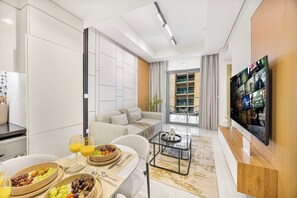 A modern living room with a sofa, coffee table, and a flat-screen TV mounted on the wall. - Skyline View Apt in Business Bay w/Pool & Sauna (Dubai)