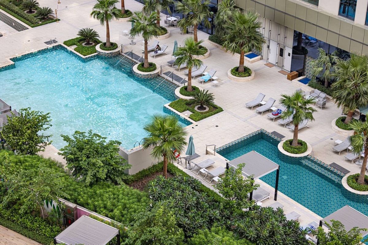 A rooftop swimming pool with multiple sun loungers and palm trees.