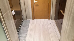 Ein Hotelbad mit Holztür, Duschbereich und Toilette.