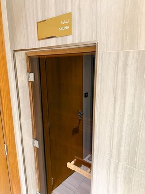 A wooden door with a sign indicating a sauna. - Skyline View Apt in Business Bay w/Pool & Sauna (Dubai)