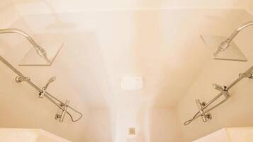 Une salle de bain équipée de deux pommes de douche et d’un panneau de commande visible.
