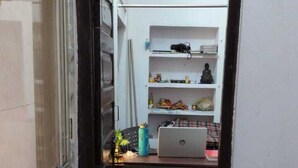A narrow hallway leading to a room with a desk, shelves, and a laptop. - Kashi Ghat Haven Homestay (Varanasi)