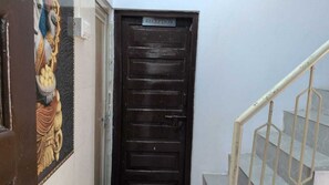 A reception door with a sign, a staircase with metal railings, and a wall with a decorative panel. - Kashi Ghat Haven Homestay (Varanasi)