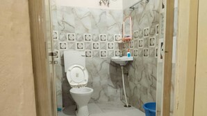A bathroom with a toilet, a sink, and a shower area. - Kashi Ghat Haven Homestay (Varanasi)