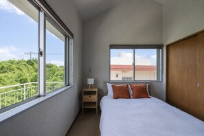 Quarto com uma cama, mesa de cabeceira, janela e guarda-roupa.