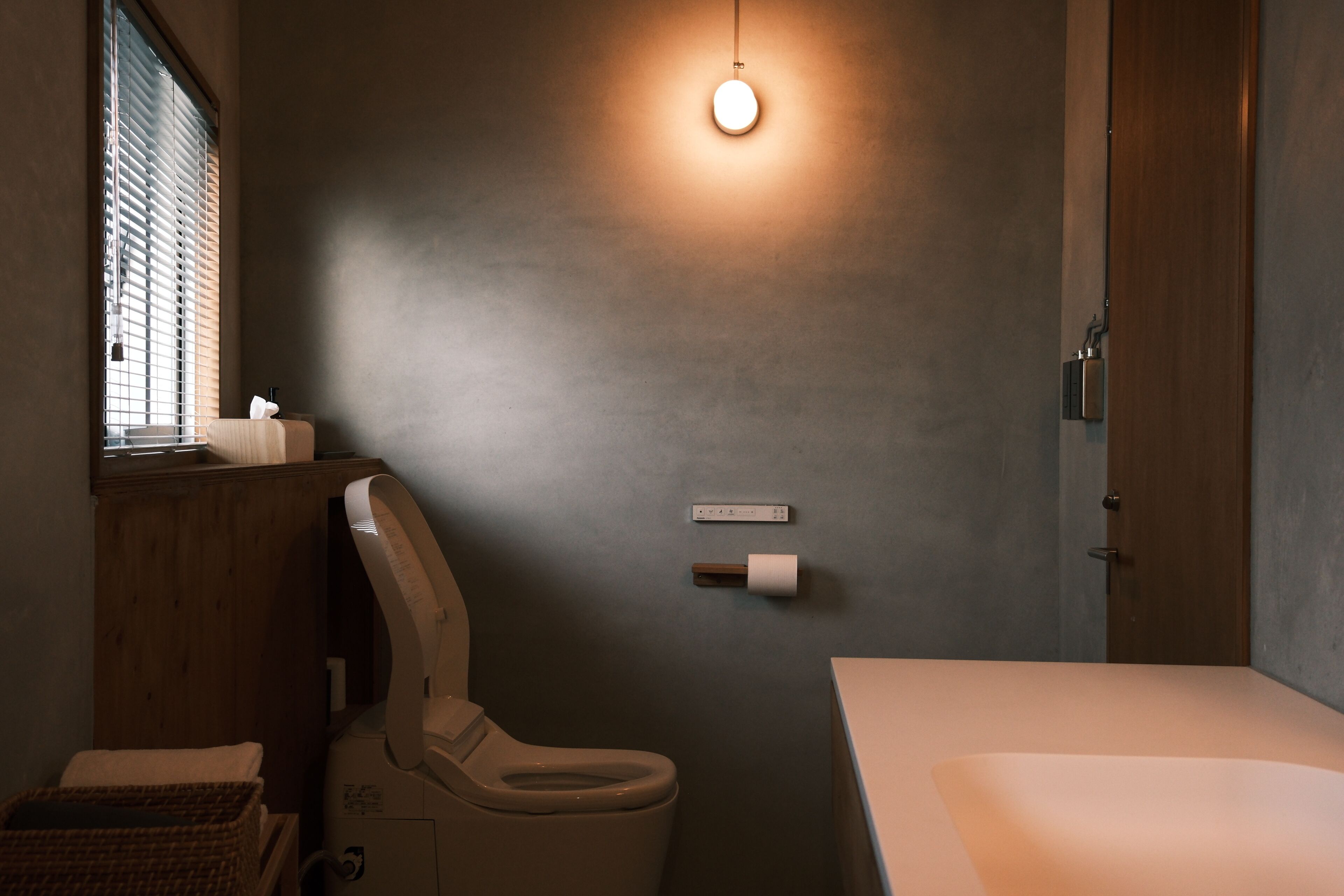 Une salle de bain équipée de toilettes, d’un bidet, d’un porte-serviettes et d’un support à papier toilette fixé au mur.