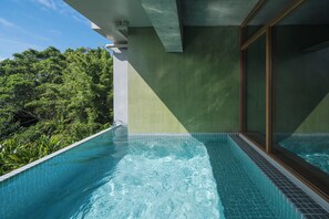 An infinity pool with clear blue water, surrounded by lush greenery and a modern architectural design.